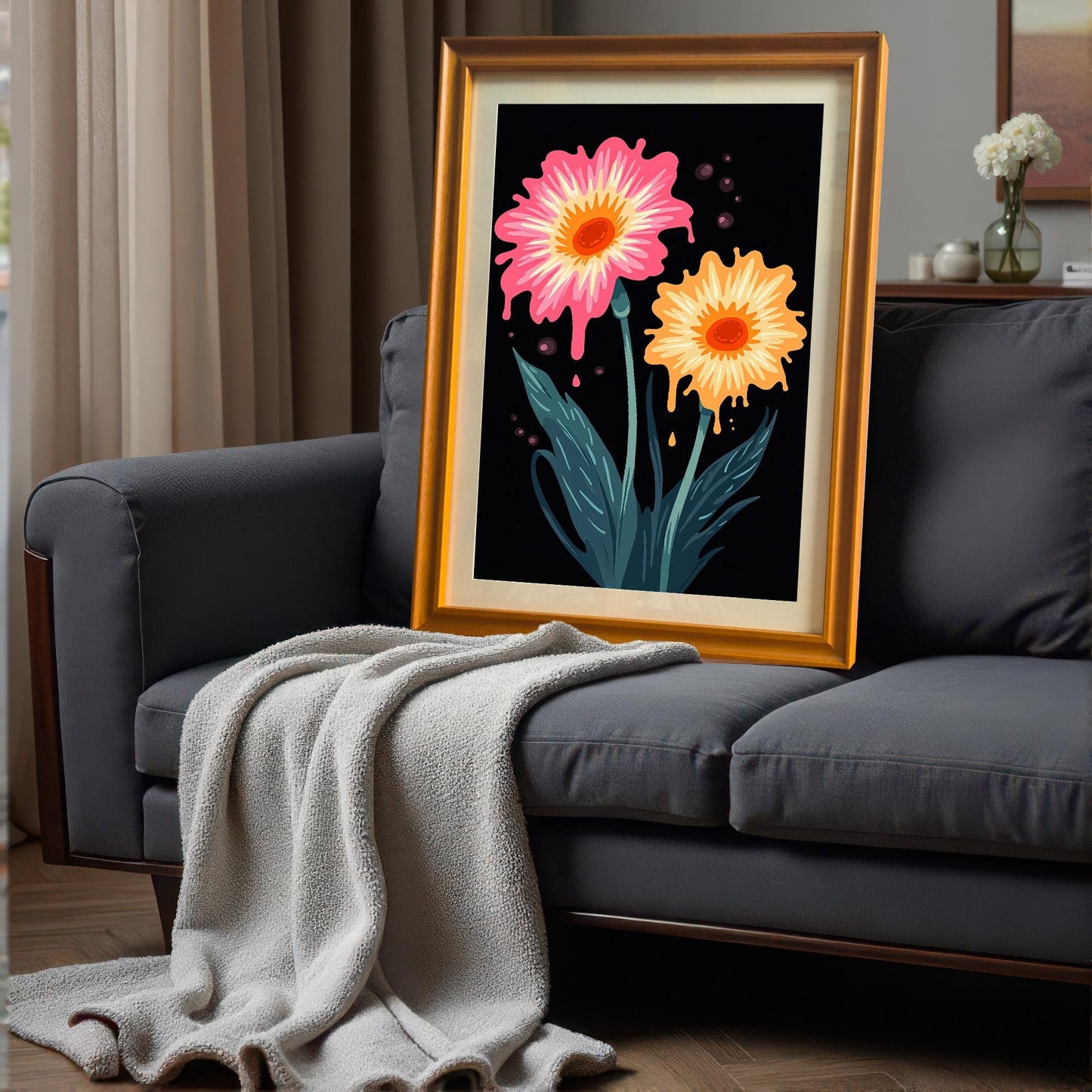 Pop art floral print in an Orange/Gold frame, leaning on the back of a dark grey sofa with a light-colored throw blanket draped over it.
