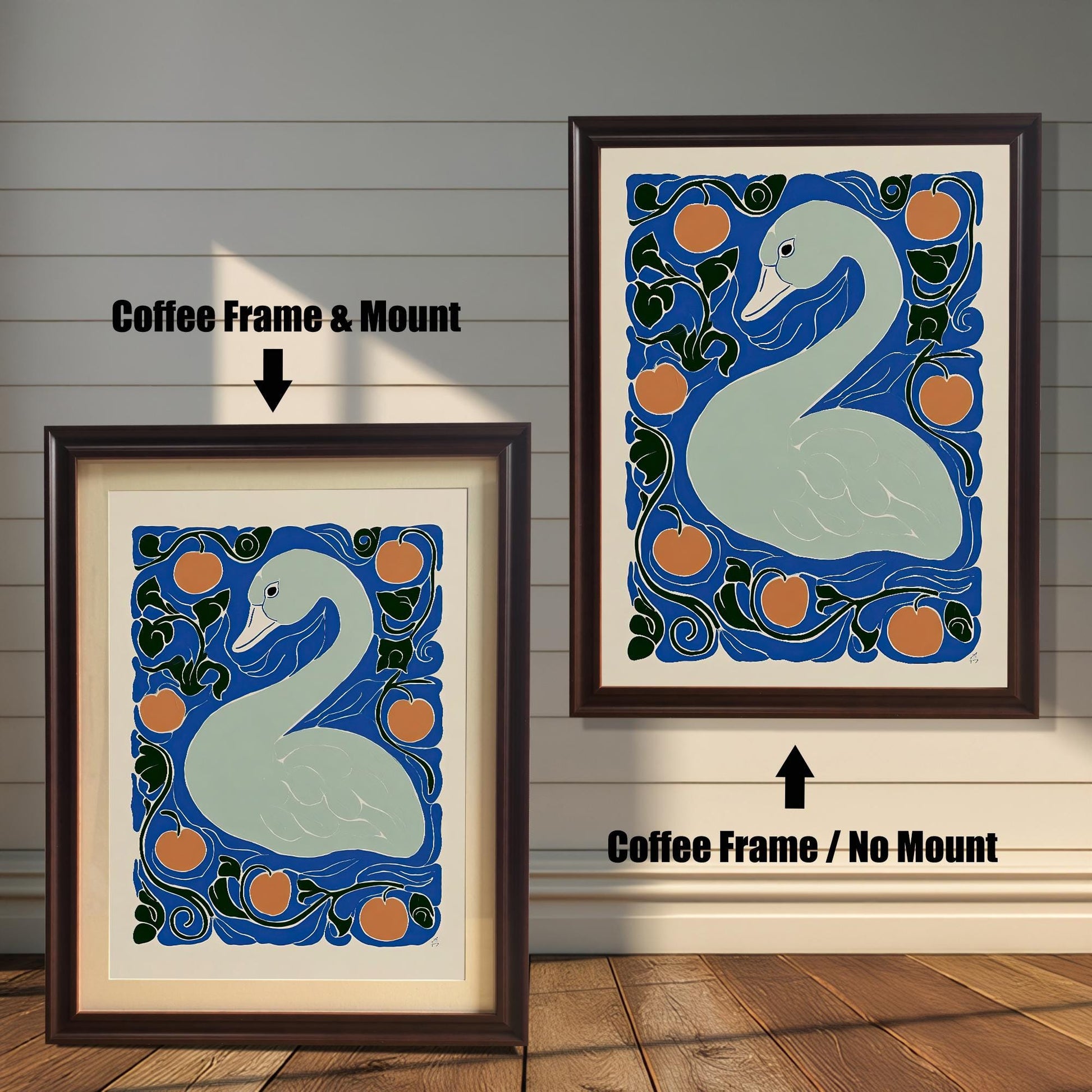Two framed prints of the swan artwork against a wooden plank wall. The print on the left is a Coffee Frame & Mount (dark brown frame with a white border/mat). The print on the right is a Coffee Frame / No Mount (dark brown frame where the art fills the frame).