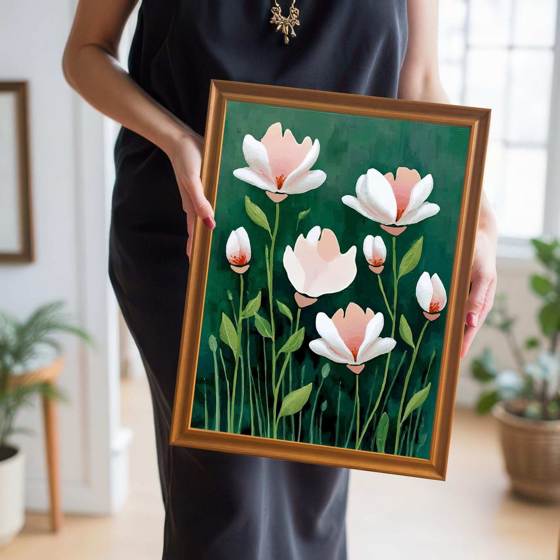 A person in a black outfit holds the framed floral print at waist level. The print is in a golden-brown (Orange) frame.