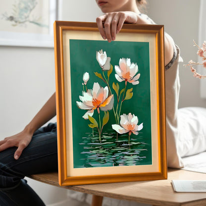 A person is holding the framed water lily print in a Gold/Orange frame at chest level, showcasing the artwork's scale. The person is sitting on a wooden bench, wearing a white shirt and dark jeans.