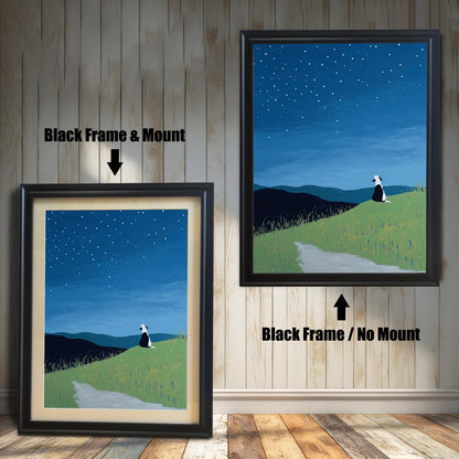 Stylized painting of a black and white dog sitting on a grassy hill under a starry night sky. The image shows two framed options: one on the left with a Black Frame & Mount (matting), and one on the right with a Black Frame / No Mount. Both are displayed against a vertical wooden plank wall and a wooden floor.