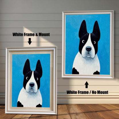 Painting of the black and white dog on a blue background. The image shows two framed options: one on the left with a White Frame & Mount (matting), and one on the right with a White Frame / No Mount. Both are displayed against a white wood-paneled wall and a wooden floor.