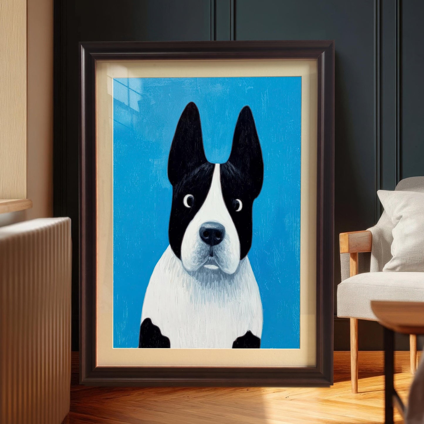 Framed painting of the black and white dog in a Coffee frame with a mount (matting), leaning against a dark wall next to a window, radiator, and a light-colored armchair.