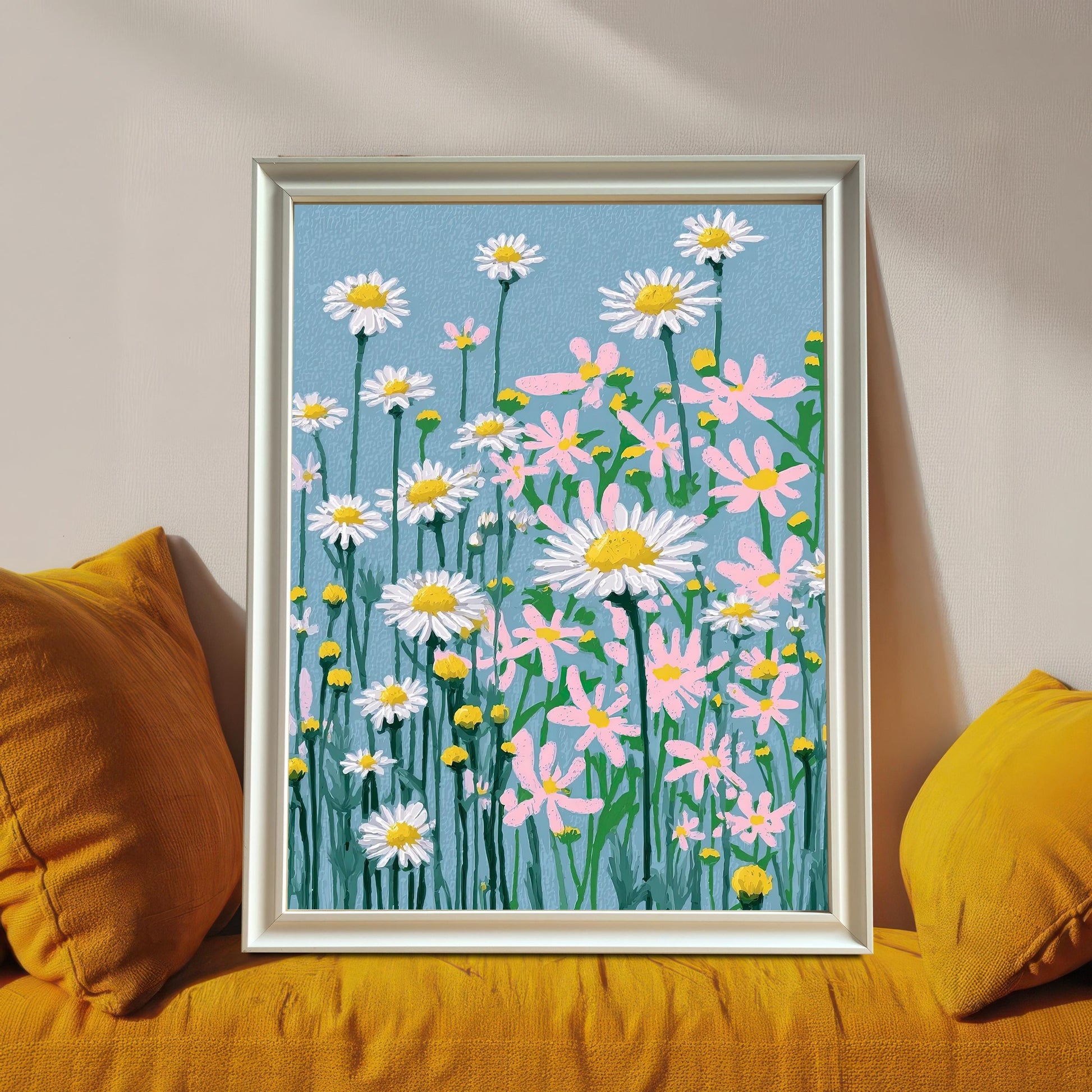 A framed art print of the daisy field illustration, set in a White frame (no visible mount), leaning on a sofa between two bright yellow pillows.
