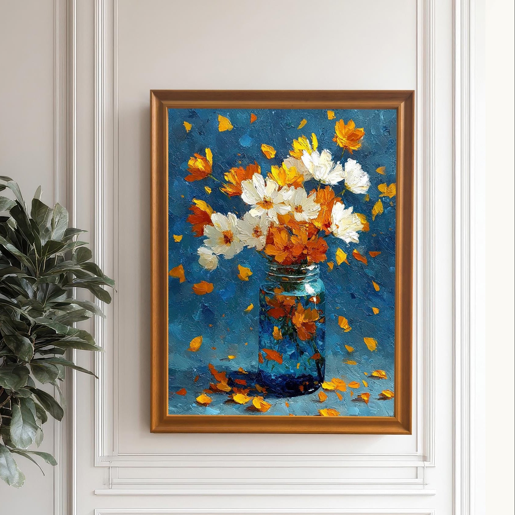 Framed floral painting in an Orange (gold) frame, hung on a white wainscoted wall. The painting features white and orange flowers in a blue jar. A large potted plant stands to the left.