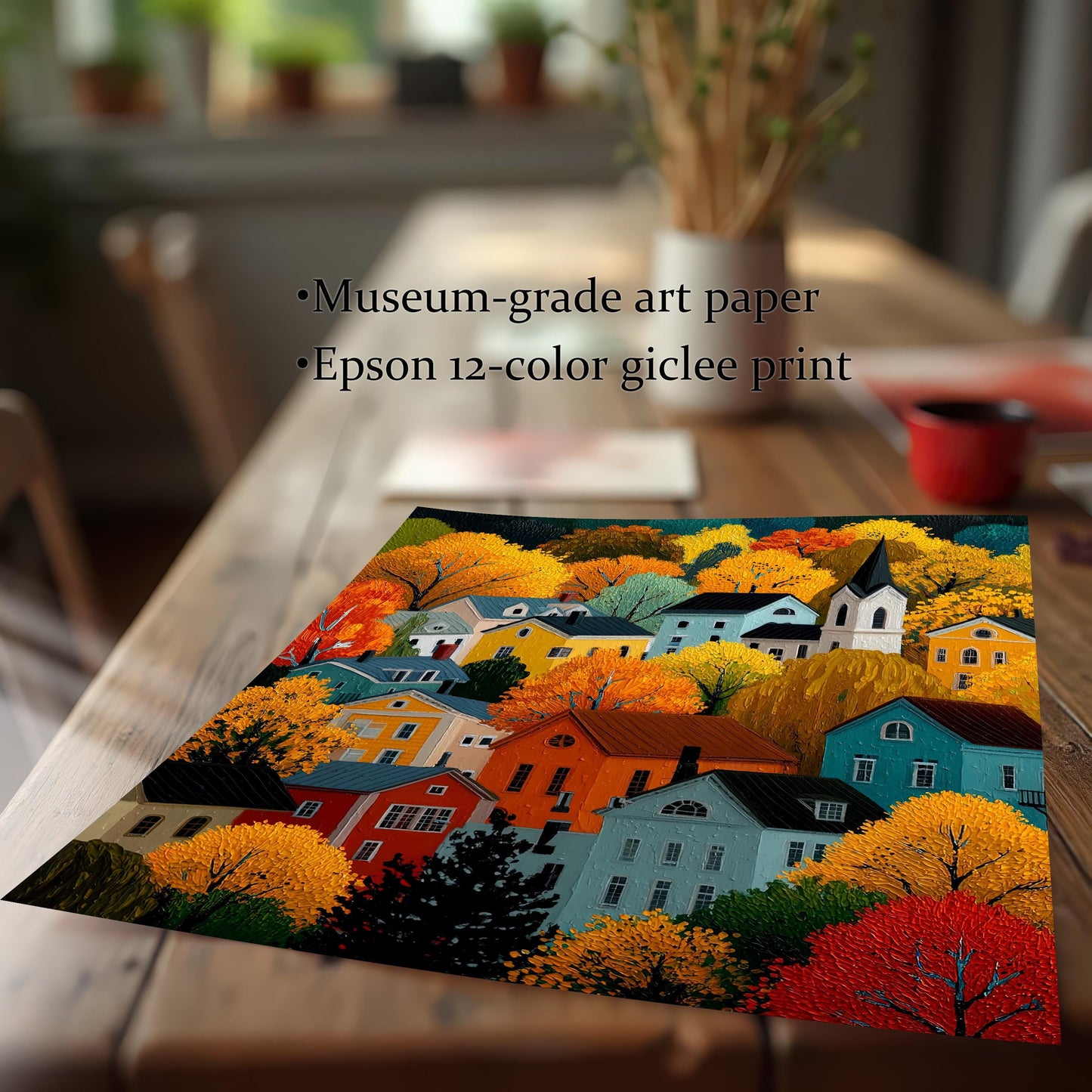Close-up of an unframed print of the colorful village scene on a wooden table. Text overlay reads: "Museum-grade art paper," "Epson 12-color giclee print."