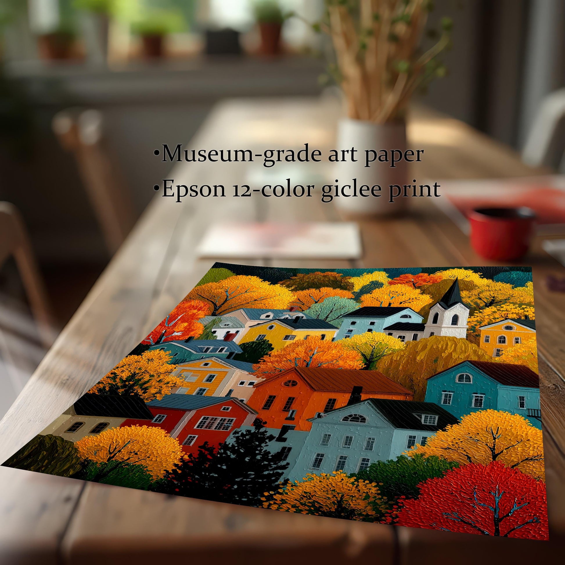 Close-up of an unframed print of the colorful village scene on a wooden table. Text overlay reads: "Museum-grade art paper," "Epson 12-color giclee print."