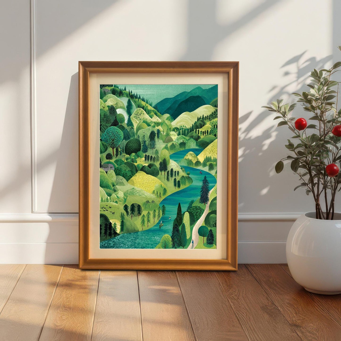 The framed landscape print in an Orange/Gold-colored frame with a mount, leaning on a wooden floor against a white wainscoted wall, next to a small potted plant with red berries.
