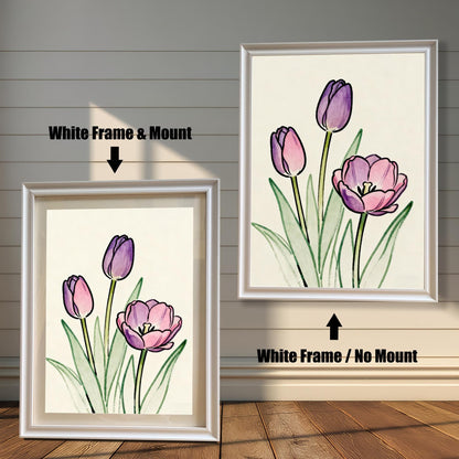 Comparison of two framed art prints on a wall. On the left, a watercolor-style print of pink and purple tulips in a framed with a White Frame & Mount (matting). On the right, the same art print with a White Frame / No Mount. Arrows indicate the frame/mount options.