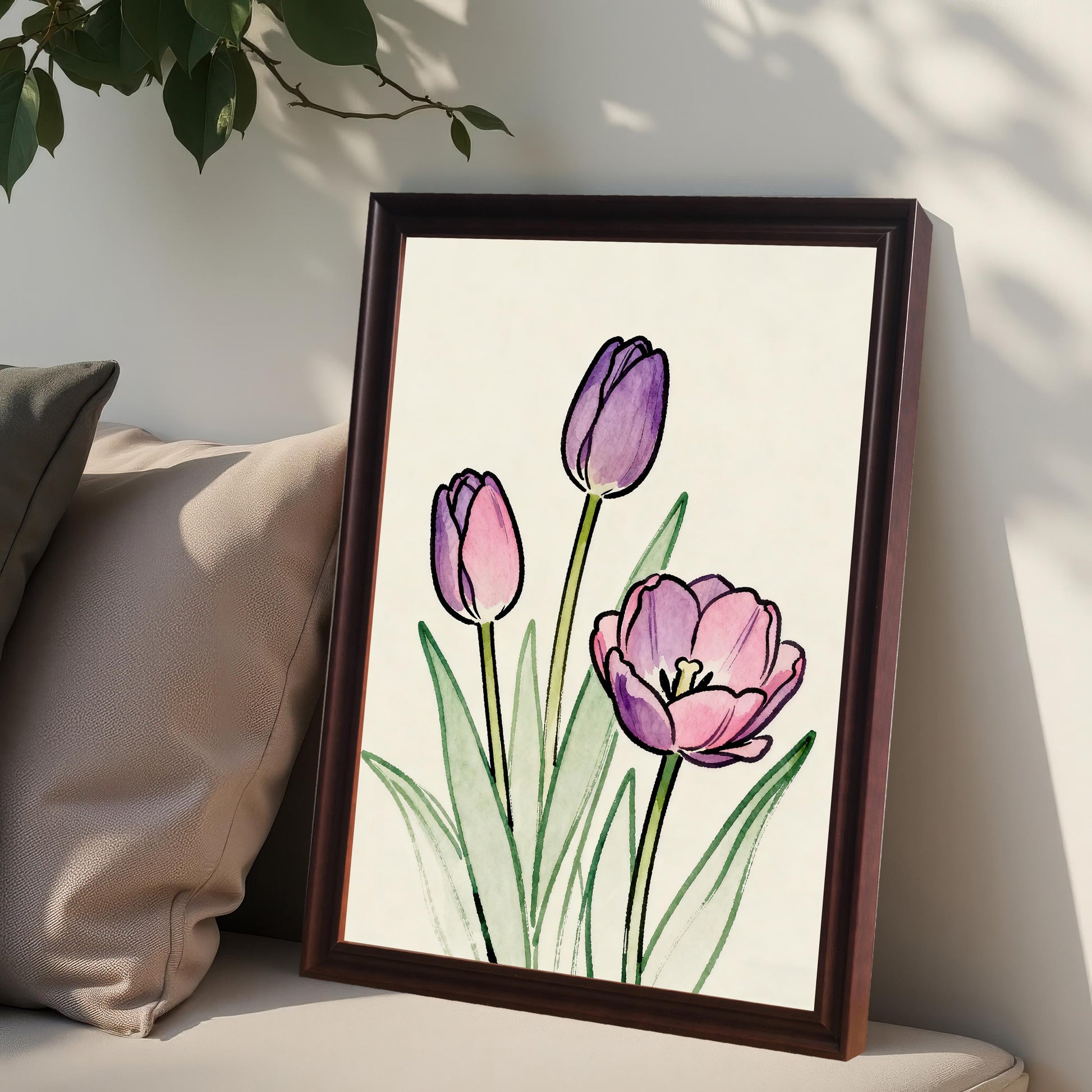 Close-up lifestyle photo showing the framed tulip art print in a dark (Coffee) frame, leaning on a cushion next to a pillow with foliage hanging above.