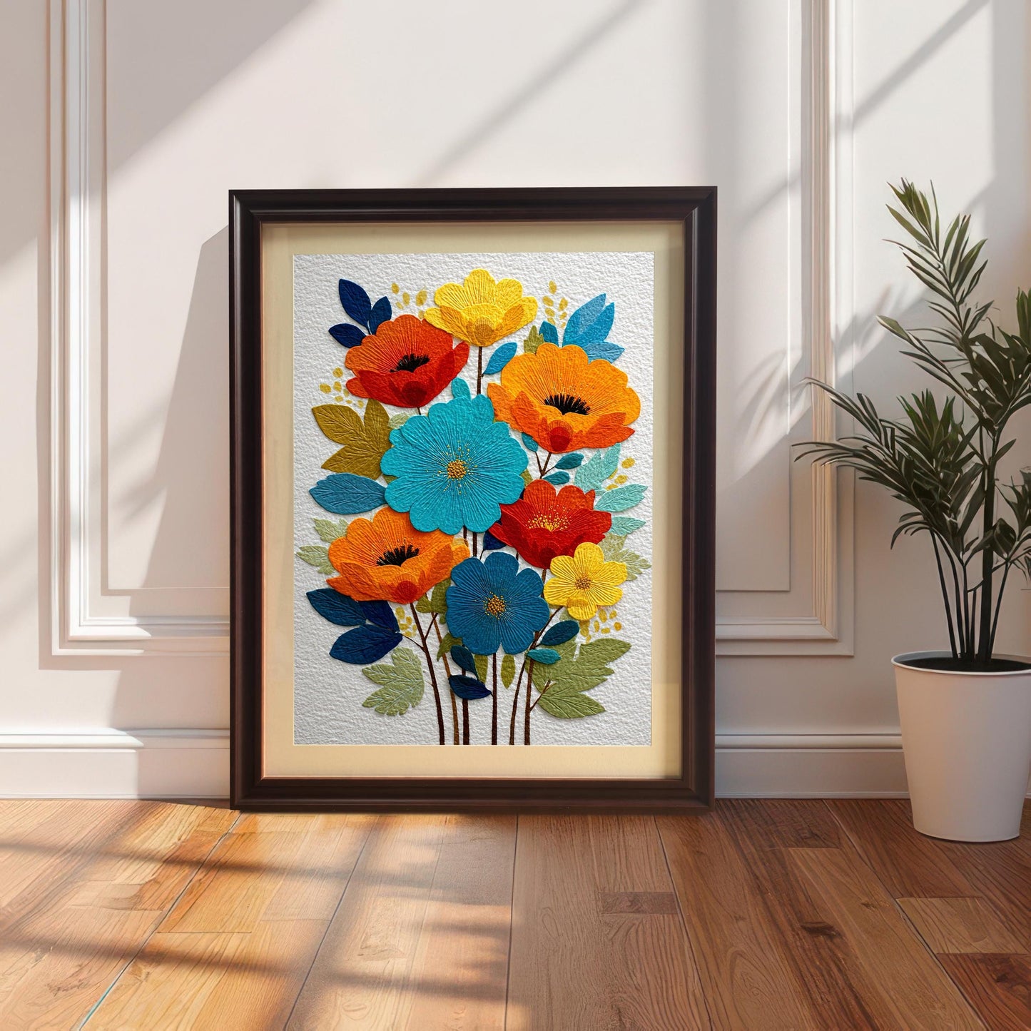 The art print featuring vibrant, embroidered-style floral art (poppies and other flowers in orange, blue, and yellow), displayed in a Coffee-colored wood frame with a mat, resting on a wooden floor against a white paneled wall next to a houseplant.