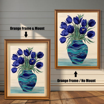 Two framed prints of the blue tulips in a turquoise vase on a rustic wood-paneled wall and floor. The left shows an Orange Frame & Mount (matting), and the right shows an Orange Frame / No Mount.