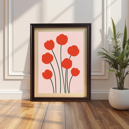 Framed print of seven red, minimalist flowers on a pale pink background leaning against a white paneled wall on a wood floor next to a snake plant. The frame is dark Coffee-colored wood with matting.