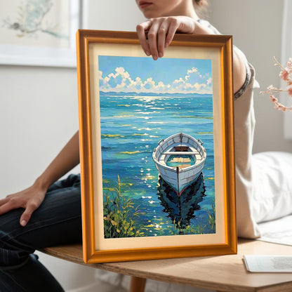 Woman sitting and holding the framed boat art print with an Orange frame, showing the full image and frame details up close.