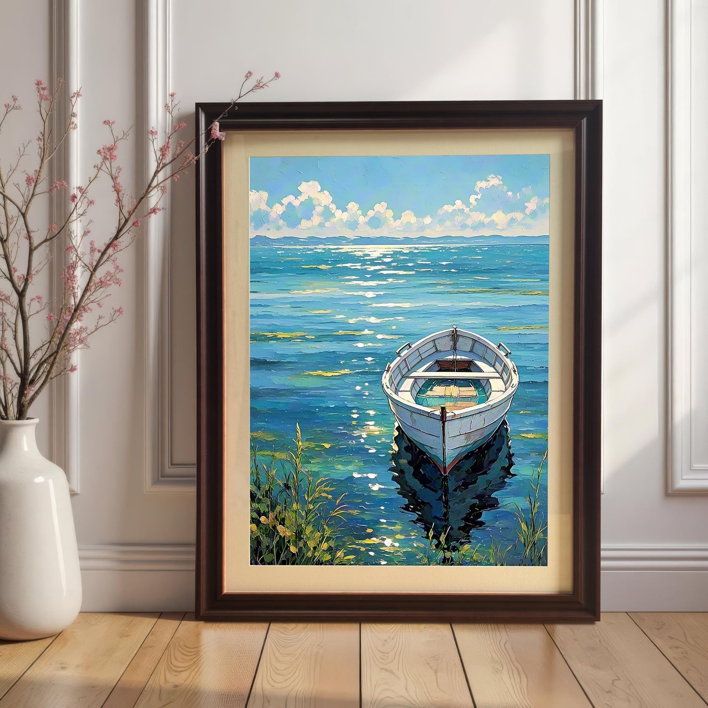 The boat art print in a Coffee-colored frame with a mat (mount) leaning on a light wooden floor and white baseboard, next to a white vase with pink-flowered branches.