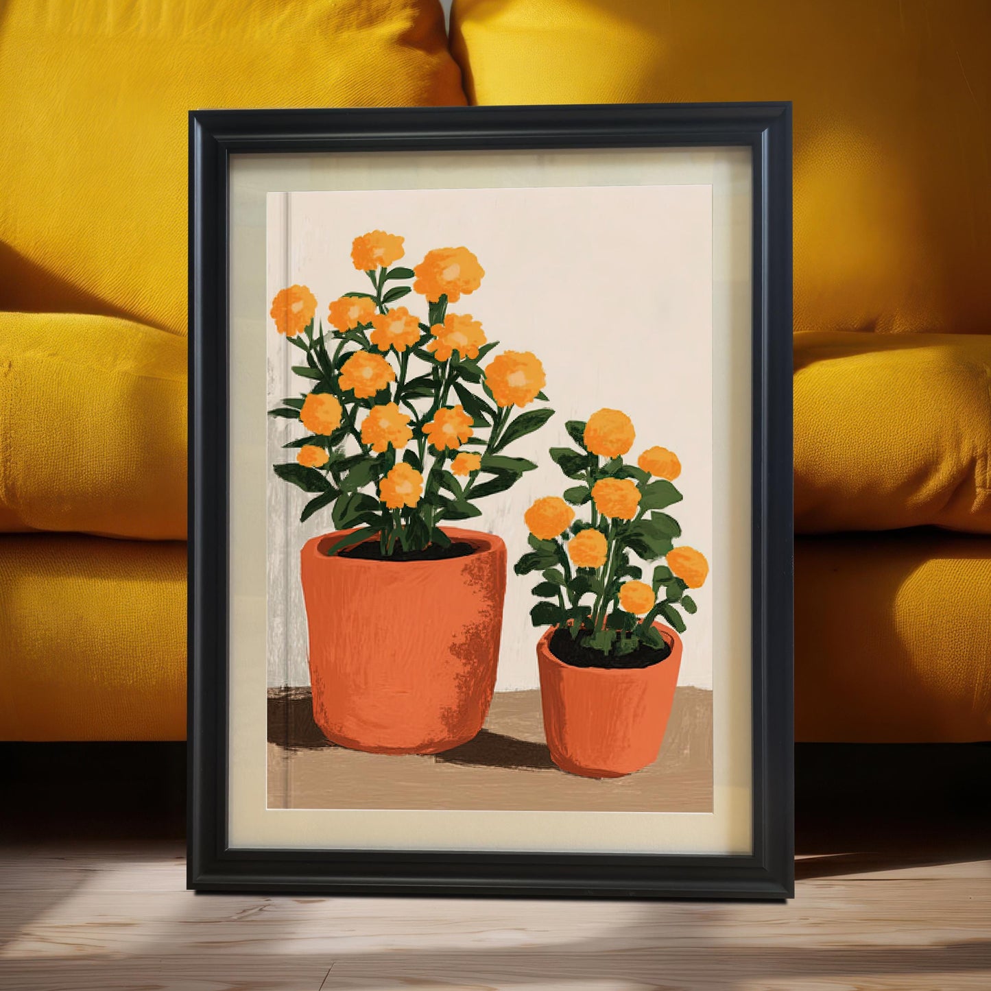 Black framed art print of two orange potted flowers, leaning on the floor against a bright yellow couch