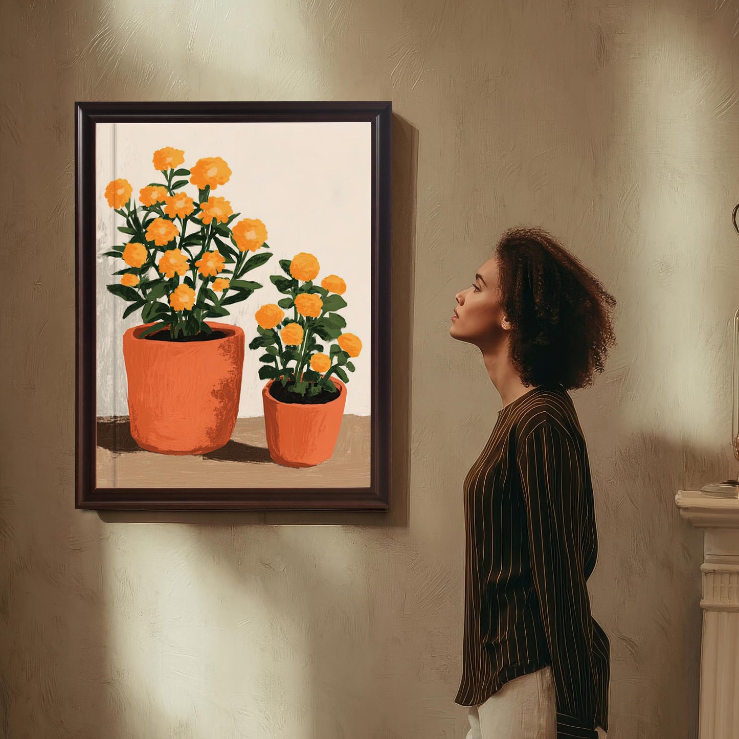 Woman standing next to a framed orange potted flower art print hanging on a textured wall, looking up at the artwork.