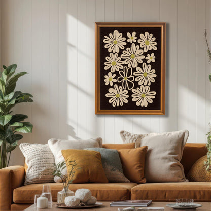 Orange framed art print of retro daisy flowers, hanging above an orange couch with various throw pillows in a cozy living room.