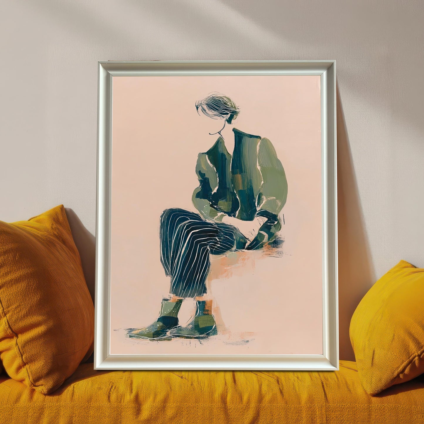 Lifestyle photo of the art print in a White wood frame propped up on a mustard yellow couch or chair between two pillows. The print features a seated figure in green and dark striped clothing on a light pink background.