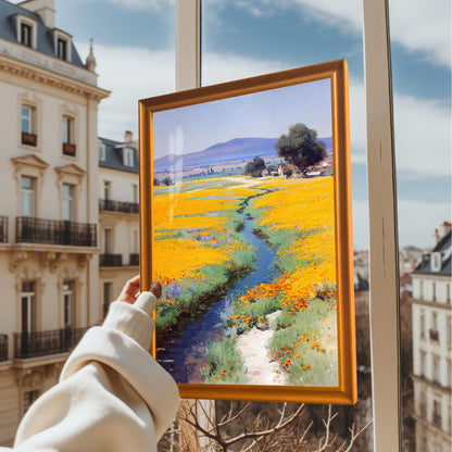 A hand holding up the framed art print (Orange Frame, No Mount) in front of a window overlooking a classic European city street scene.