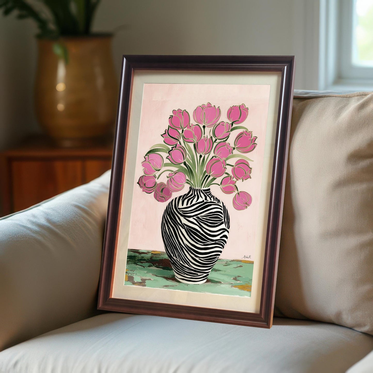 Abstract art print featuring pink tulips in a zebra striped vase in a coffee (dark brown) wood frame with a mat/mount, resting on a beige sofa in a cozy interior setting.