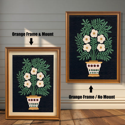 A comparison of two framed art prints showing an off-white floral bouquet in a pot against a dark background. One is an Orange Frame & Mount (matting), and the other is an Orange Frame / No Mount.