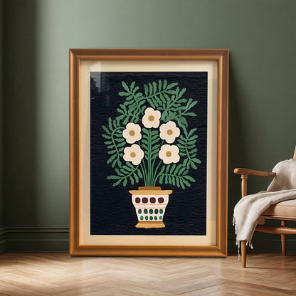 A large, framed print of the folk floral art resting on a wooden floor against a dark green wall, next to a wooden armchair. The frame is a warm Orange/Gold color.
