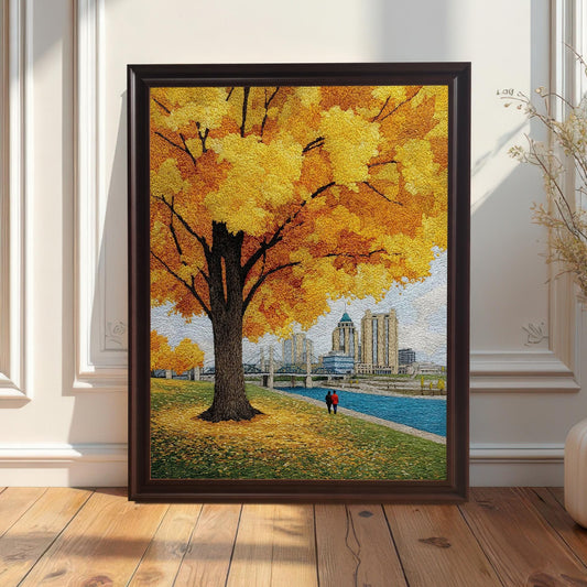 Full view of the textured yellow autumn tree and city print in a dark brown/coffee frame leaning against a white wainscoting wall, next to a tall white vase with dried flowers.