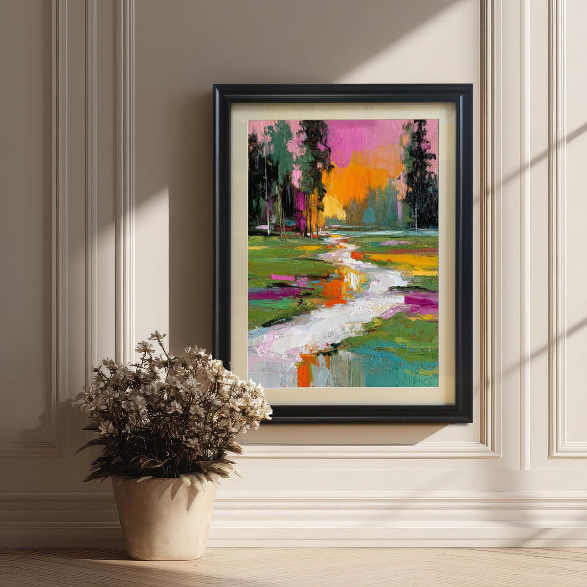 Abstract textured landscape art print in a black wood frame with a mat/mount, leaning against a white wainscoted wall next to a pot of dried white flowers.