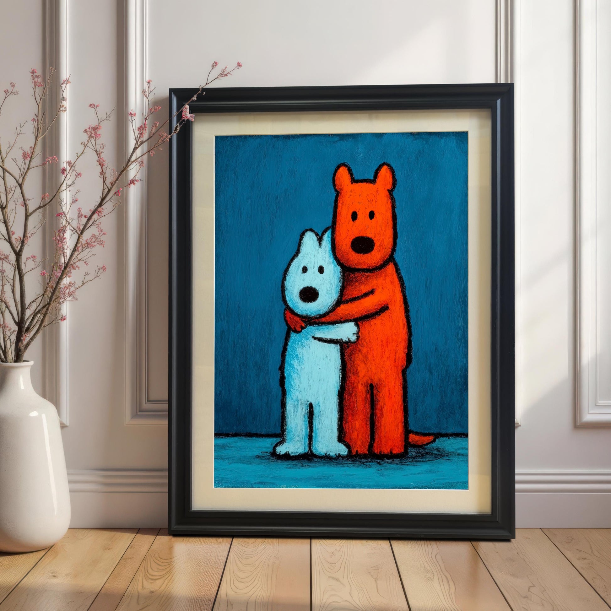 Framed art print of two stylized, hugging dogs (one orange, one light blue) in a black wood frame with a mat/mount, leaning on a wooden floor against a white wainscoted wall next to a white vase with small pink branches.