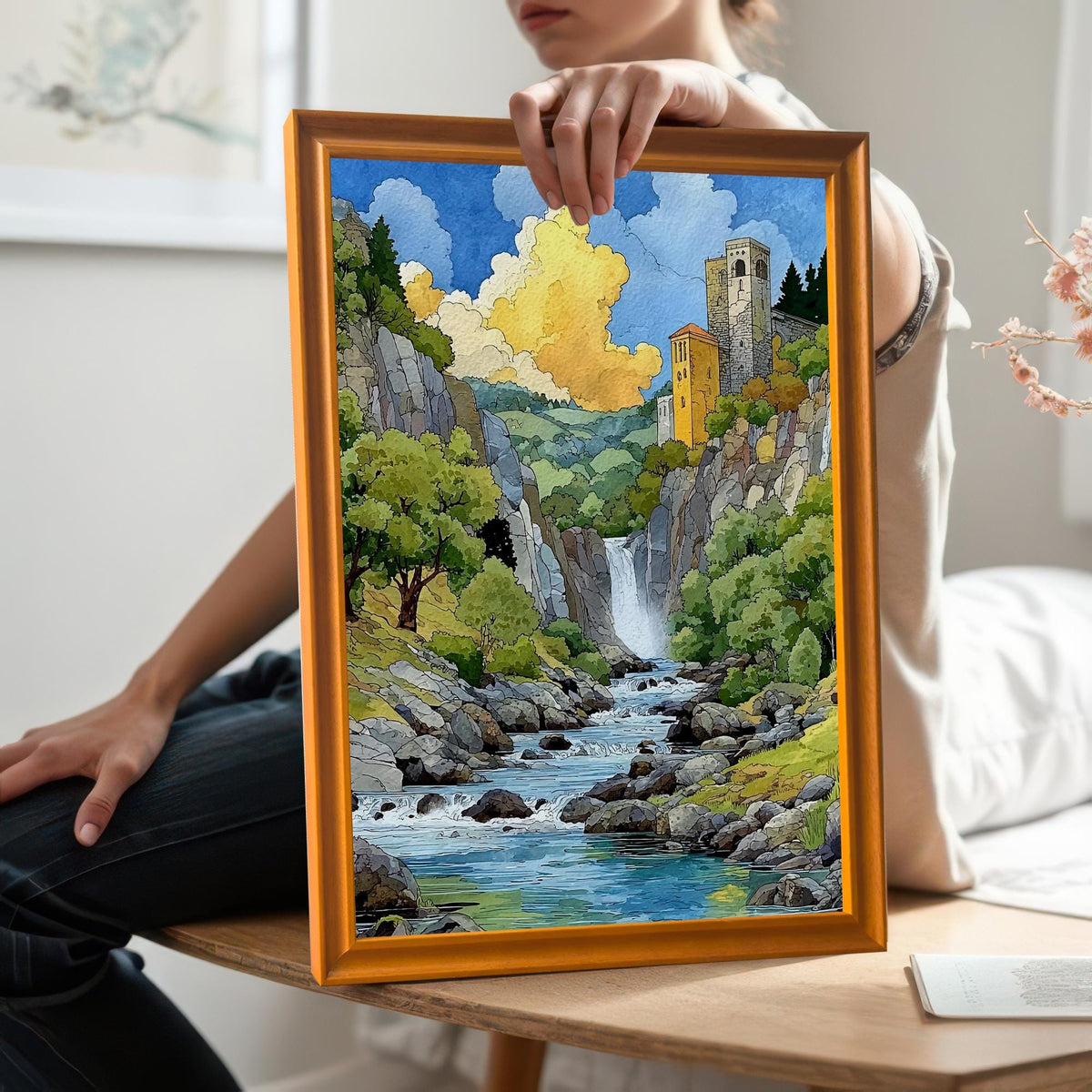 A person holds the vibrant waterfall landscape art print in an Orange Wood Frame, sitting on a wooden bench, showing a close perspective of the artwork.