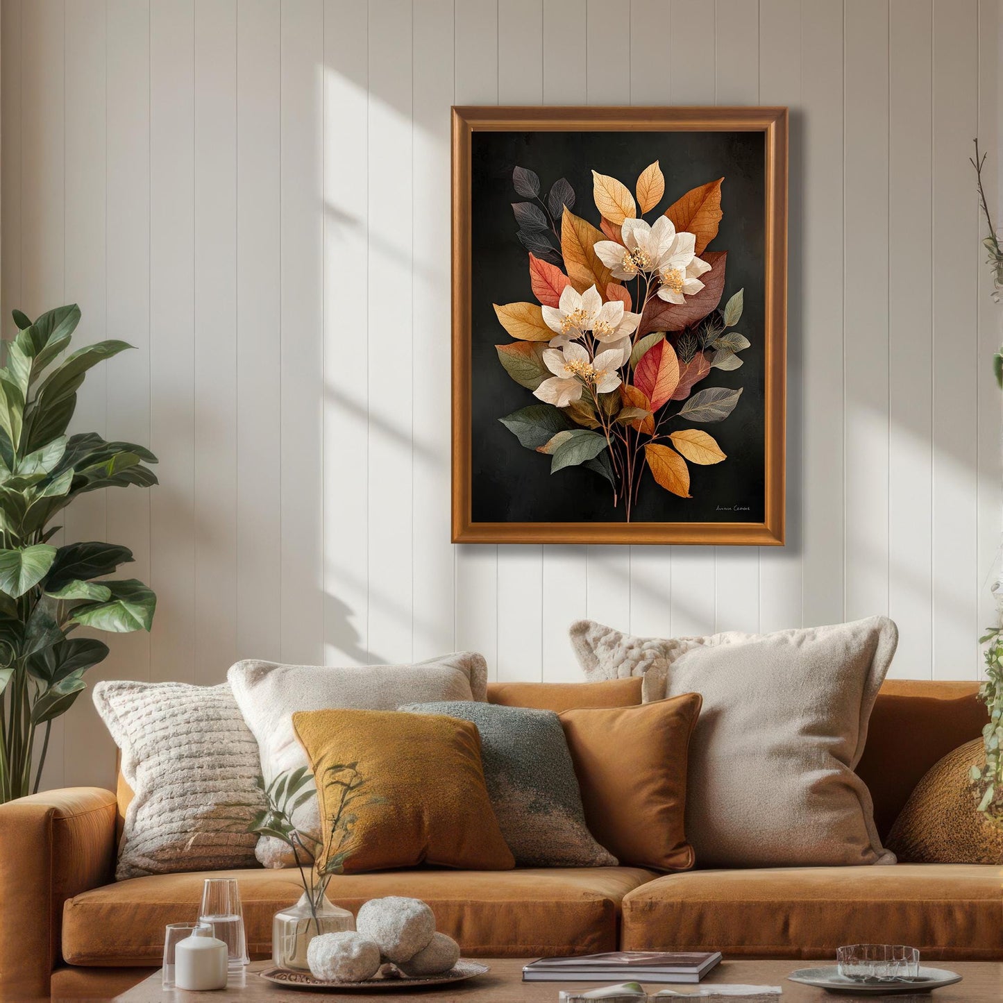A framed art print of the autumn floral bouquet hanging above a mustard-colored couch with various throw pillows. The frame is a warm brown (Orange color). The image highlights the art in a living room setting with natural light, complementing a warm, cozy color palette.