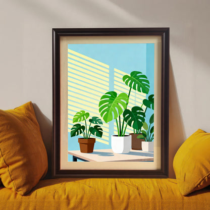 Close-up view of the framed 'Monstera Plants' art print. The print is in a dark brown/black wood frame and rests on a yellow cushion, featuring bright green Monstera plants in pots against a blue wall with venetian blind shadows.