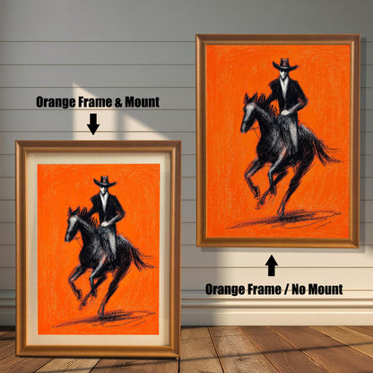 Close-up view of a framed art print featuring a striking black charcoal sketch of a cowboy riding a horse against a bright orange background. The image shows two frame options: an Orange (light brown/golden) colored wood frame with a mount (matting) and an Orange wood frame with no mount around the print.
