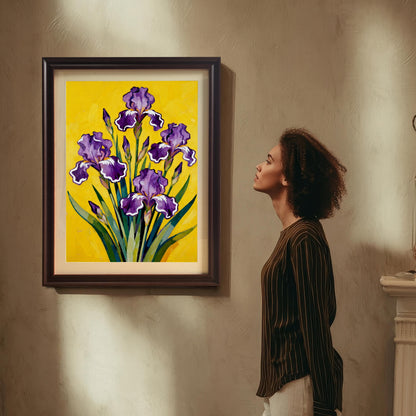 A woman in a brown striped shirt and white pants stands, looking up at a large, dark brown Coffee framed art print featuring a vibrant painting of purple Irises on a bright yellow background, which is hanging on a textured beige wall.