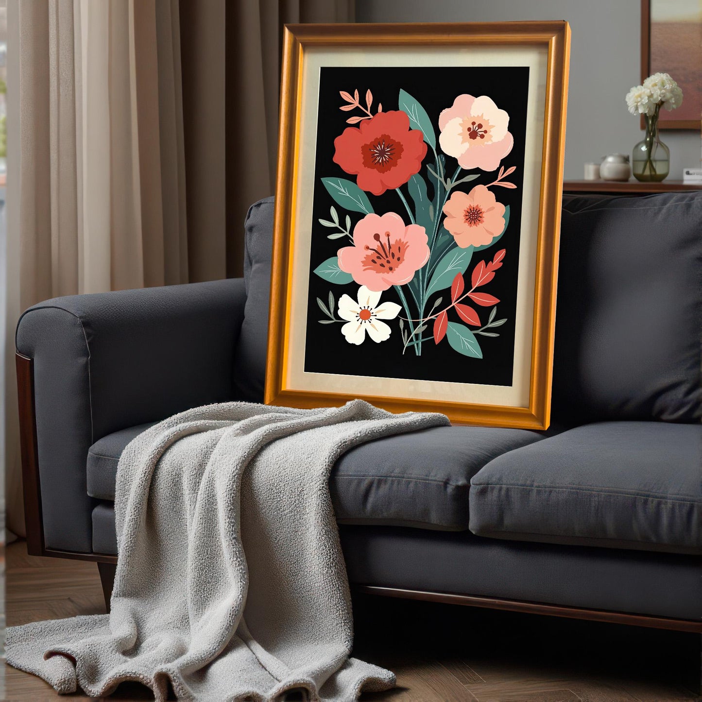 Gold-framed floral art print leaning on a dark gray couch with a light gray throw blanket. The setting is an indoor living area.