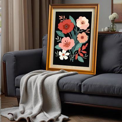 Gold-framed floral art print leaning on a dark gray couch with a light gray throw blanket. The setting is an indoor living area.