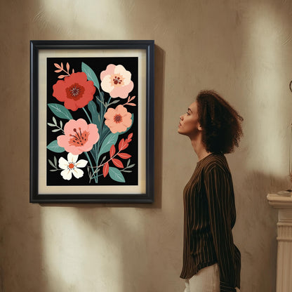 A woman with curly hair, wearing a striped shirt, standing in a dimly lit room and looking up at a framed floral art print hanging on a textured wall. The art has a black frame and a mount (mat).
