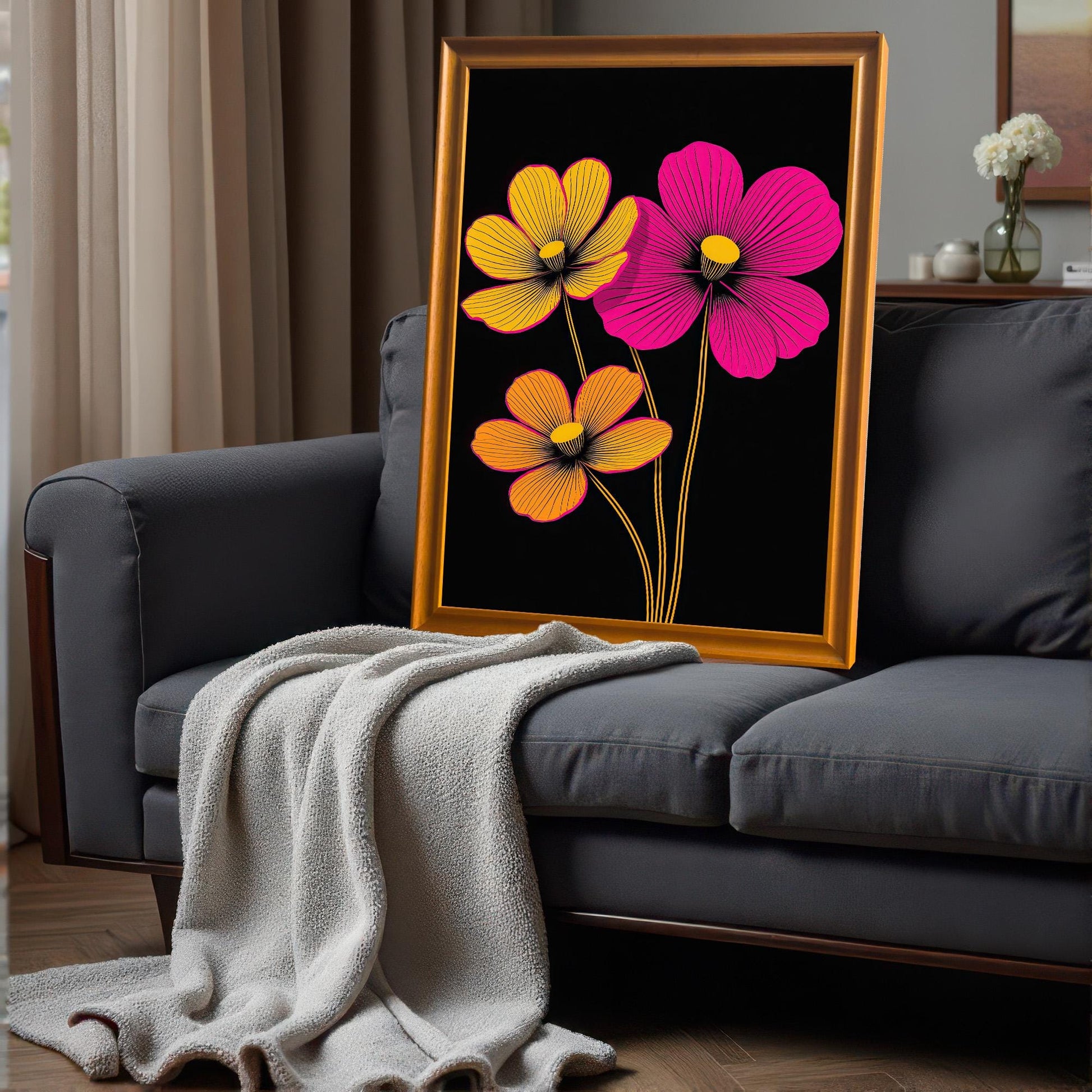 Abstract neon floral art print in an Orange/Gold frame, leaning on the back of a dark gray sofa with a light-colored throw blanket draped over it.