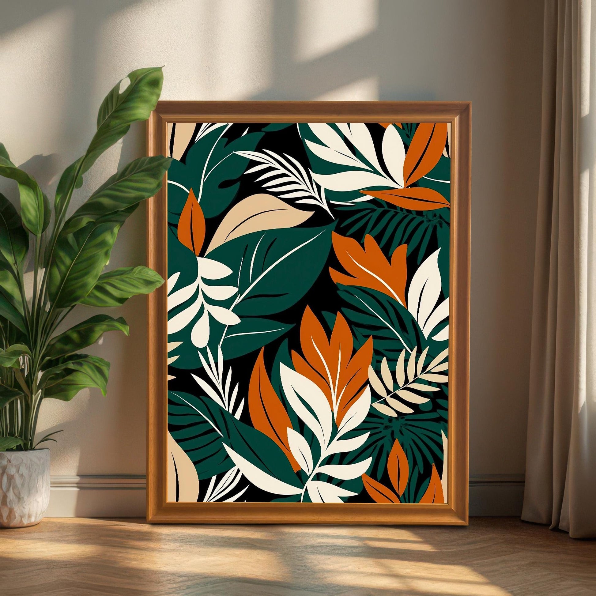 Large, tropical leaf art print in a Brown/Wood frame, propped up on a wooden floor next to a large potted houseplant in bright light.