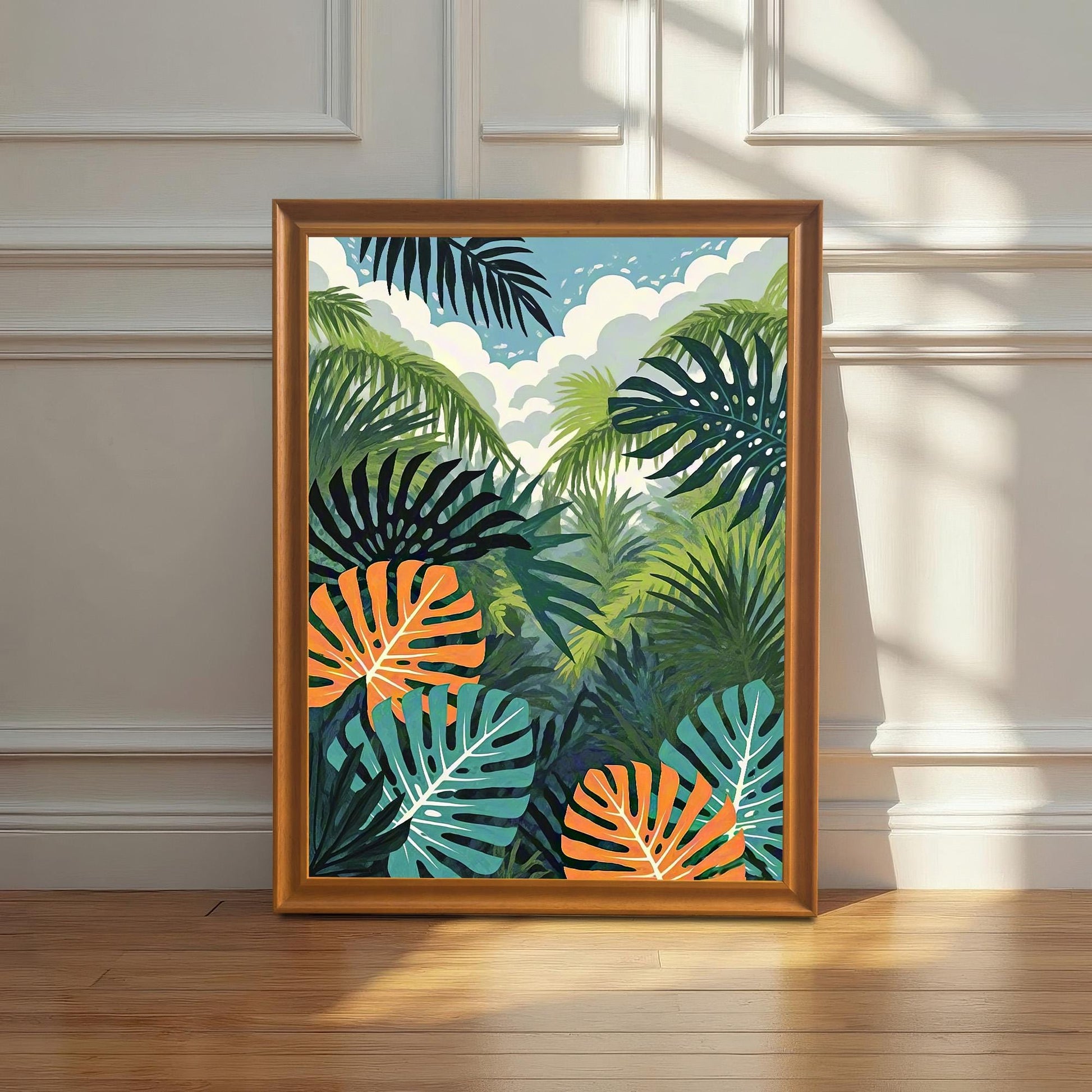 A vibrant, framed art print featuring a tropical jungle scene with green palm fronds, dark teal leaves, and bright orange-and-white monstera leaves, leaning against a white wainscoting wall on a hardwood floor, bathed in natural sunlight.