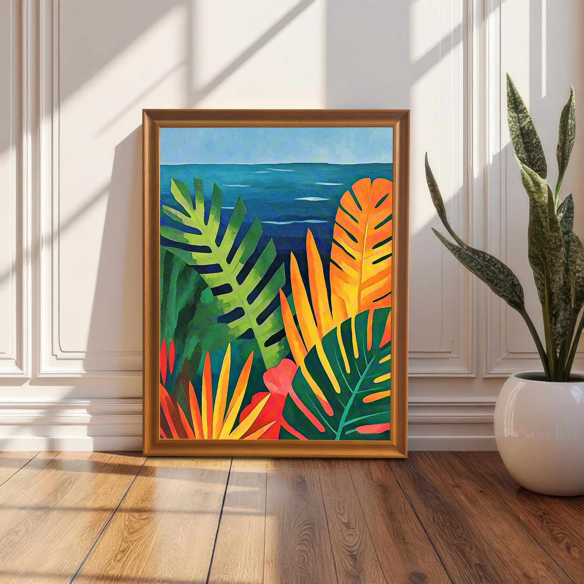 Lifestyle image of the tropical seascape framed art print in a gold/Orange Wood Frame, leaning on a wood floor against a white paneled wall next to a potted snake plant. Strong sunlight and shadows create a warm effect.