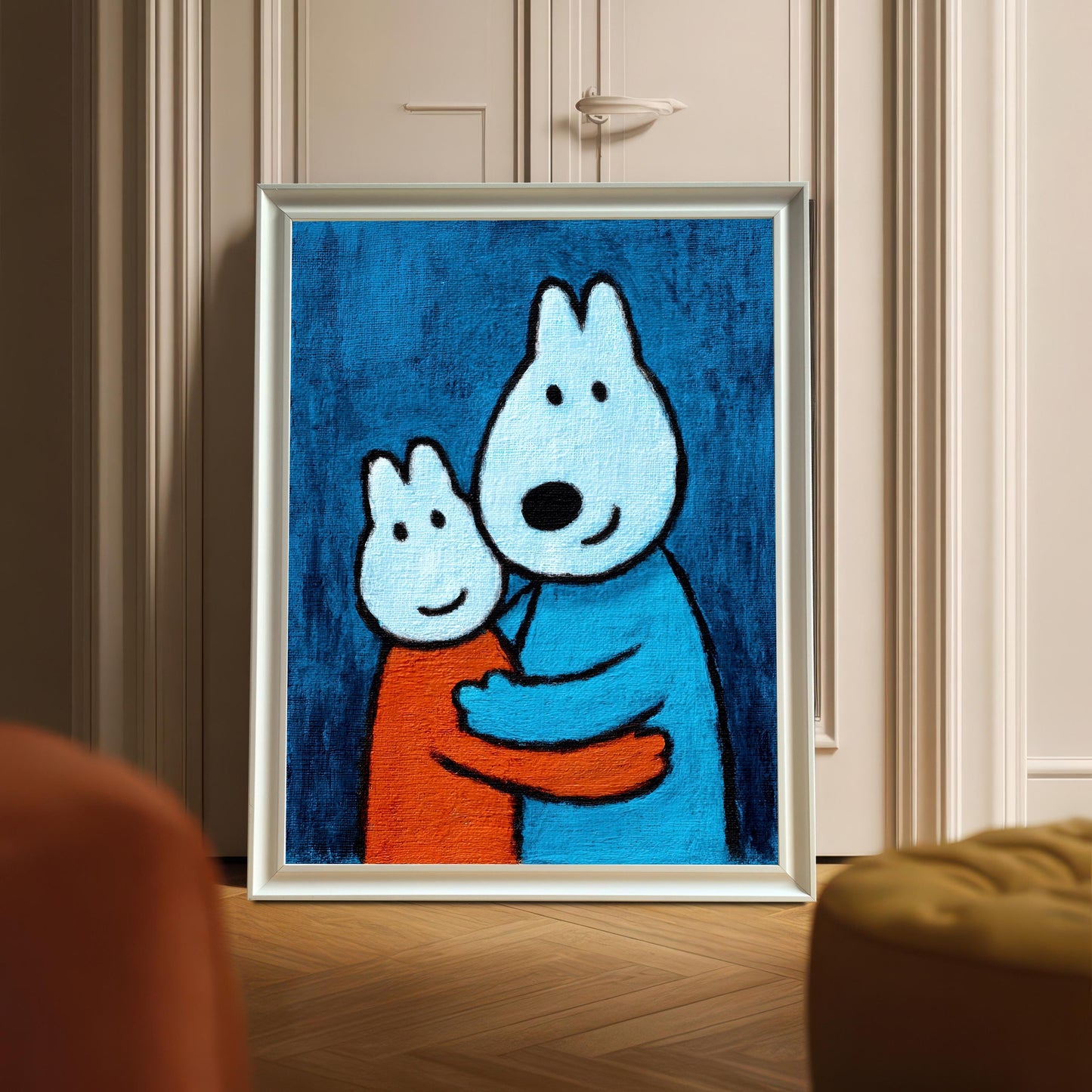 A vertical framed art print in a White wood frame without a mount leaning against a paneled door, with the scene partially blocked by an orange chair and yellow ottoman.