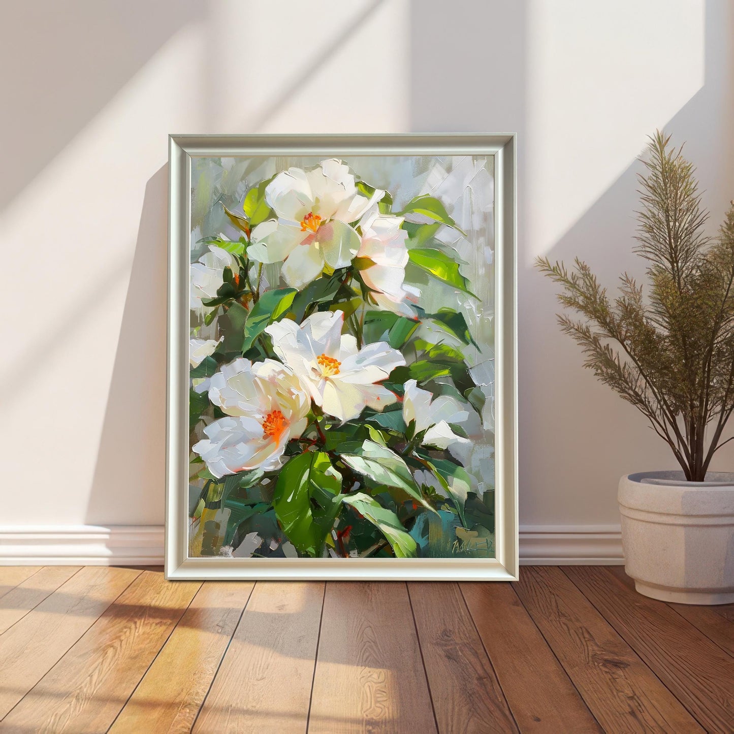 A beautiful white flower oil painting in a white wood frame, leaning against a white wall on a wooden floor, next to a tall, slender potted plant. Sunlight casts dramatic shadows across the scene.