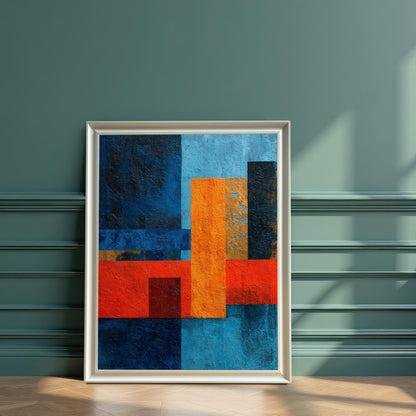 Abstract art print with geometric shapes in dark blue, bright red, and orange, displayed in a white wood frame leaning against a dark teal, wainscoted wall.