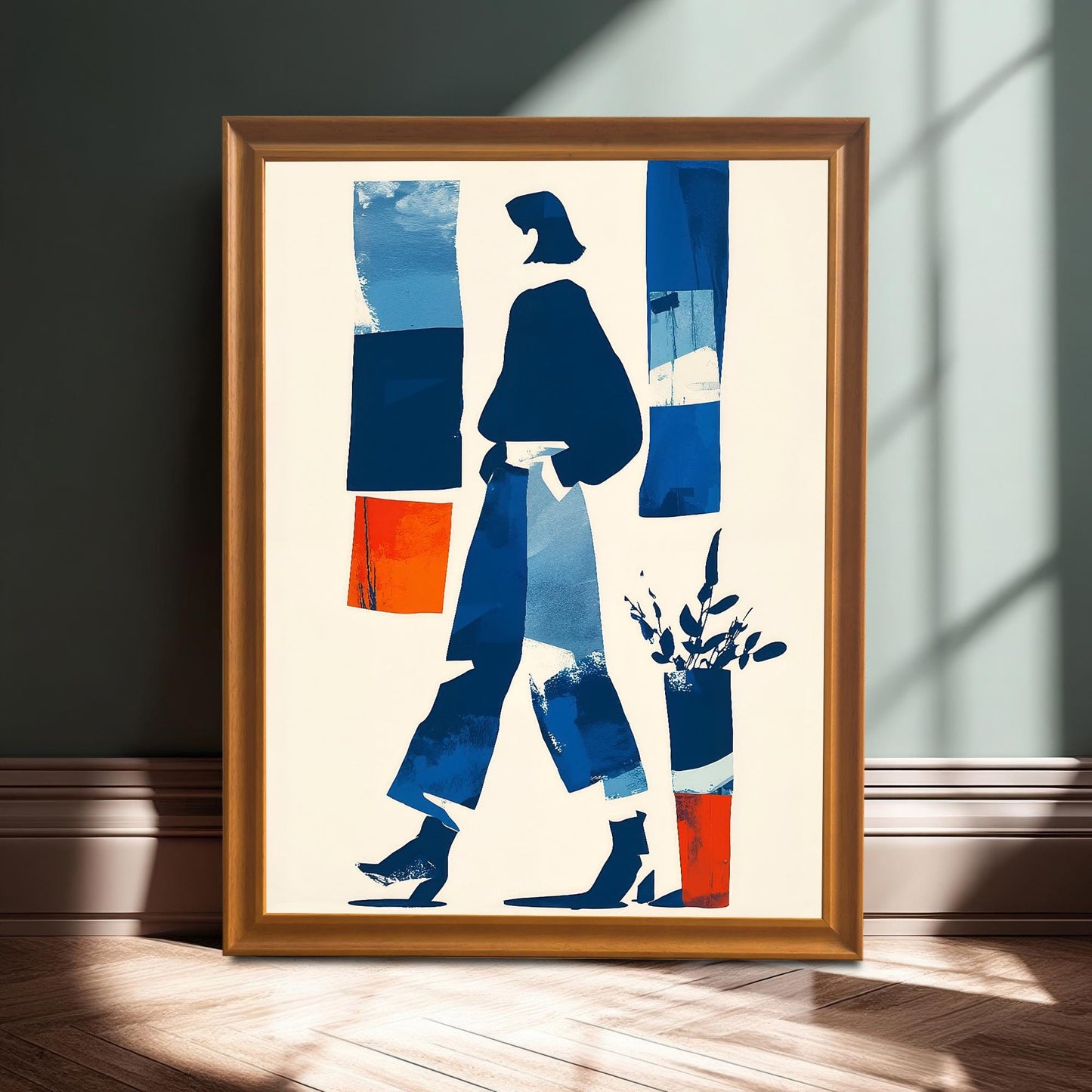 A full shot of the abstract art print in an orange/light brown wooden frame, leaning on the floor against a dark wall, illuminated by a strip of sunlight.