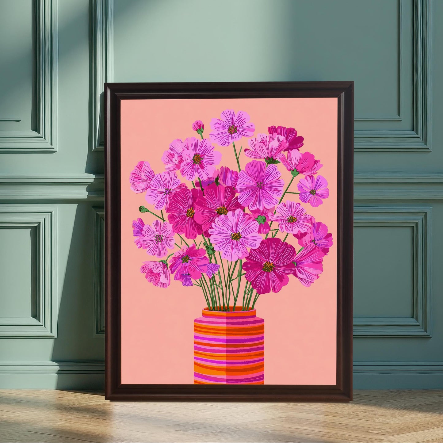 Vertical image of a framed art print featuring bright pink and magenta Cosmos flowers in a striped orange vase on a pink background. The print is in a dark frame, leaning against a teal/green paneled wall.