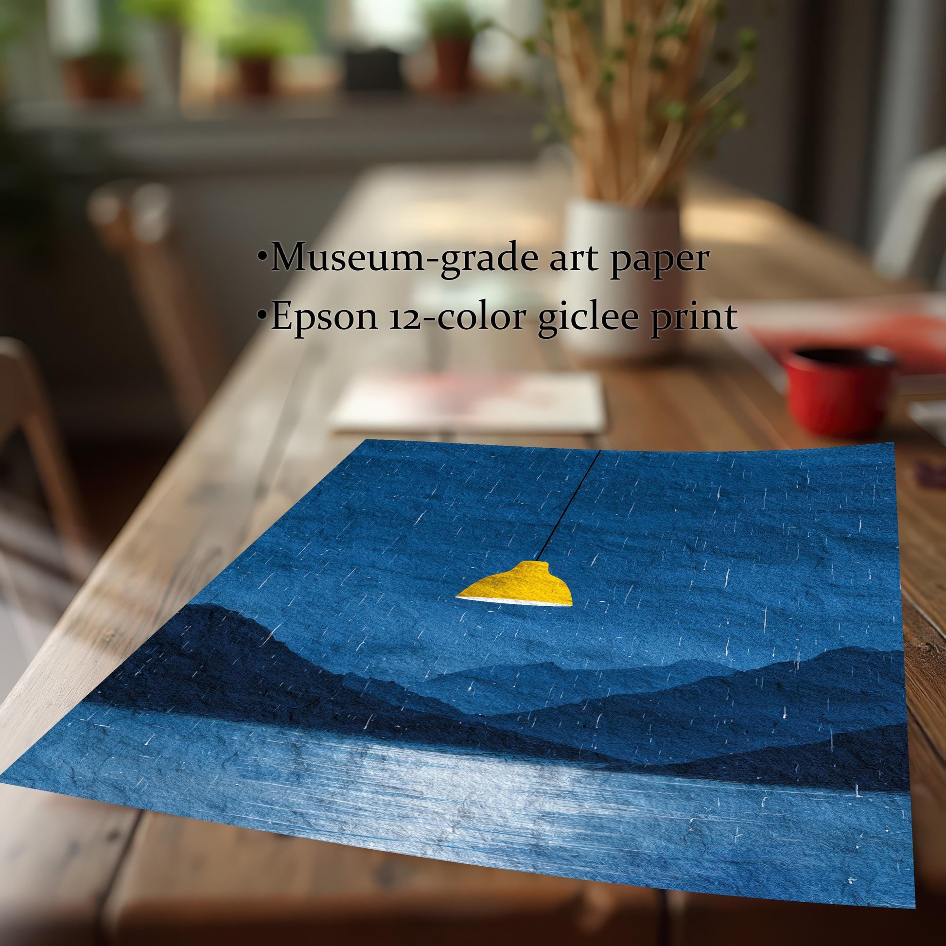 A close-up shot of the dark blue rainy landscape art print lying on a wooden table. Text highlights the quality: Museum-grade art paper and Epson 12-color giclee print.