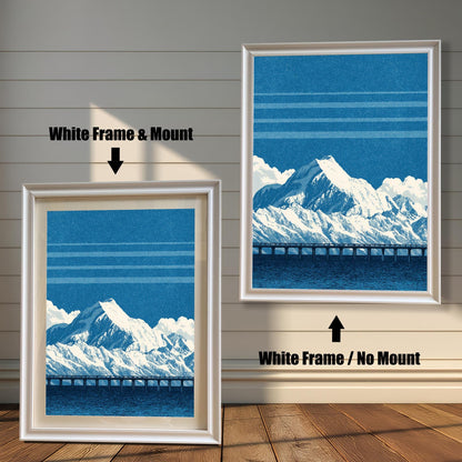 A comparison image showing two framed art prints on a wooden wall. The print on the left is in a White Frame & Mount (white frame with a light mat). The print on the right is in a White Frame / No Mount (white frame, no mat). Both feature the blue mountain and bridge design.