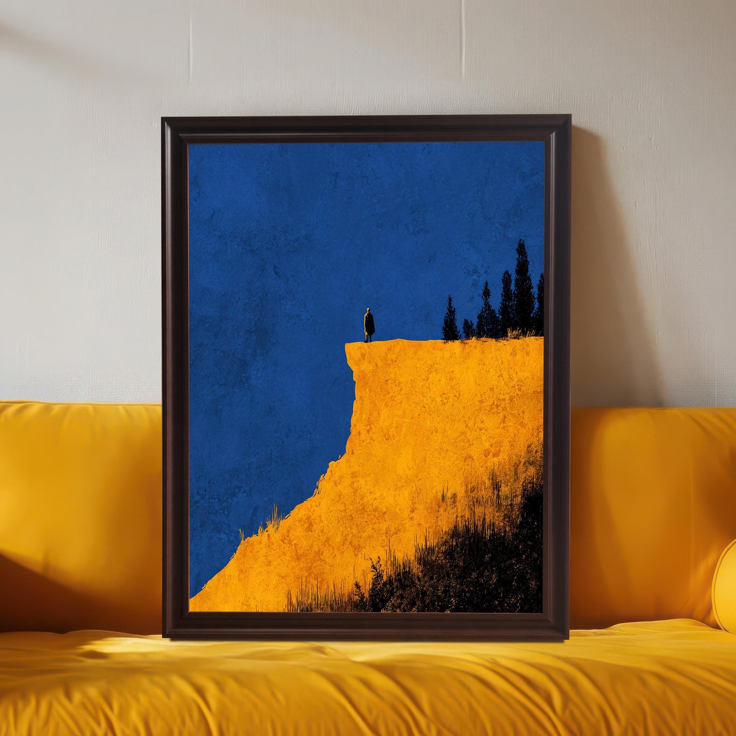 Large framed abstract cliff print in a Coffee (dark brown) frame (no mount), leaning on a bright yellow sofa. The colors are vivid and contrasting (blue and yellow).